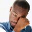 A man tiredly rubs his eyes, representing the exhaustion that can come with family caregiving.
