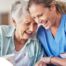 A woman in scrubs laughs with a senior woman, representing how caregiving can be a great career choice.